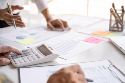 2 osoby pracują nad optymalizacją gospodarki odpadowej w firmie przy biurku, na kt&oacute;rym leżą dokumenty i kalkulator