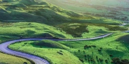 kręta, malownicza droga położona pośr&oacute;d wzg&oacute;rz pokrytych żywo zieloną trawą