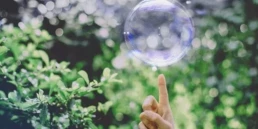 palec, kt&oacute;ry za moment przebije bańkę mydlaną symbolizujący oferty pracy w doradztwie środowiskowym Interzero