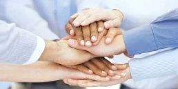 dłonie pracownik&oacute;w złożone jedna na drugiej symboilizujące oferty pracy w dziale operacji Interzero