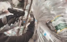 ręce trzymające skaner i worek z butelkami PET